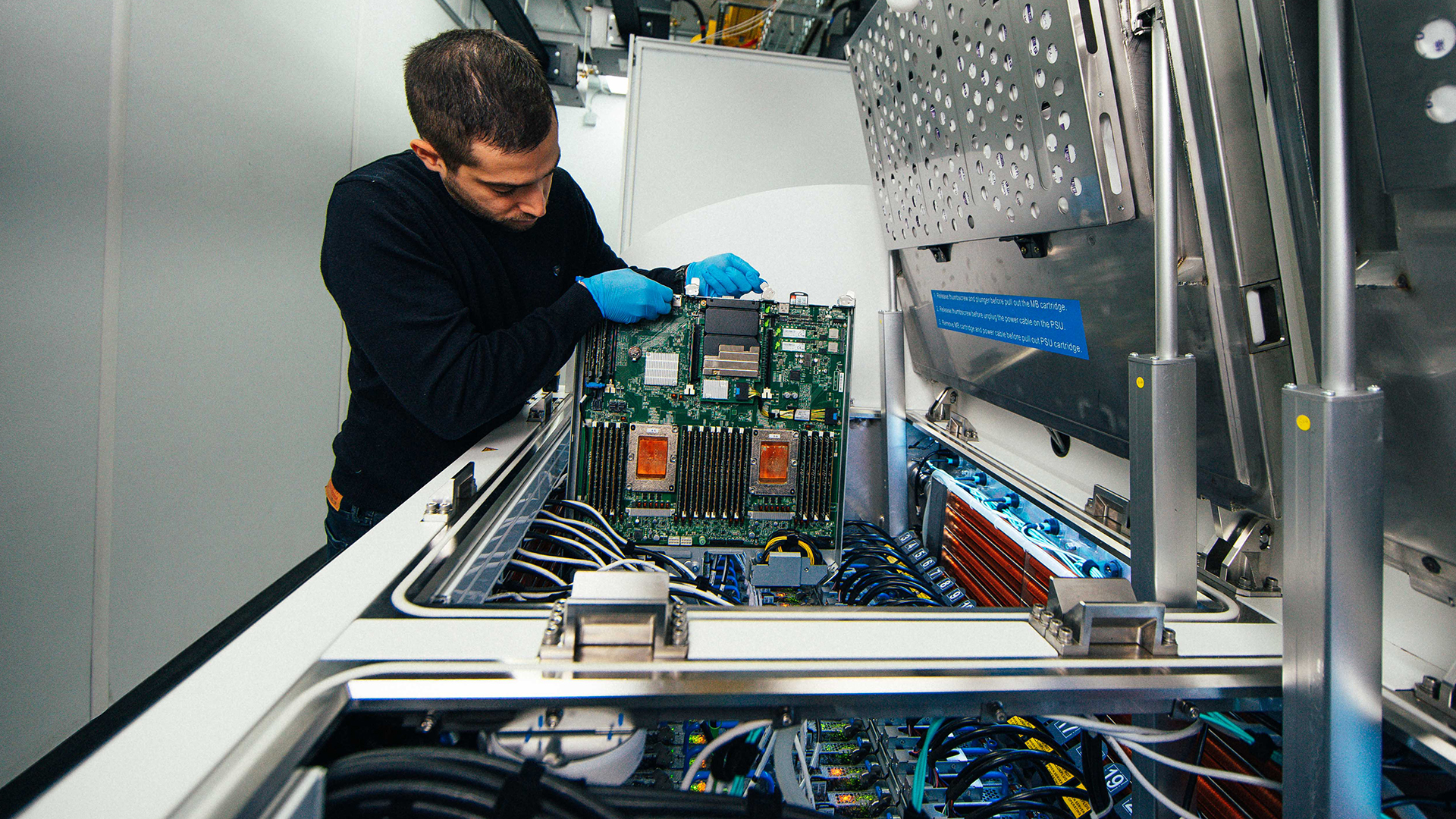 Ioannis Manousakis, a principal software engineer with Azure, removes a server blade from a two-phase immersion cooling tank at a Microsoft data center.