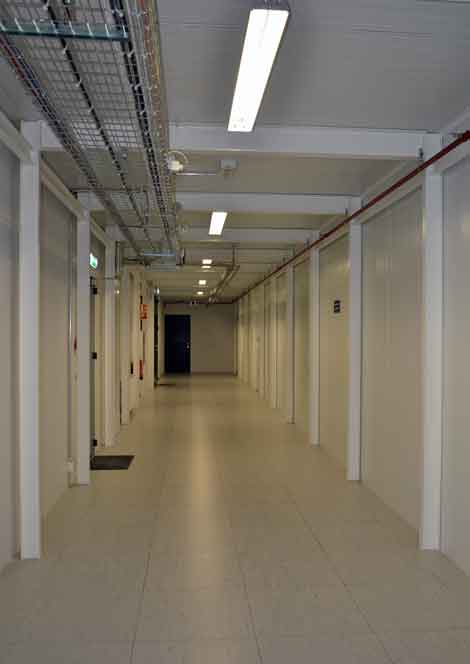 This photo gives an idea of the length of part of the Verne Global data center. Pipes and cables run through the hallway. The door to the data hall is marked with prohibitions, such as no photography, no eating and drinking, and so on. (Photo by Colleen Miller.)