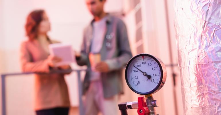 Selective focus of manometer for data center cooling system near blurred engineers.