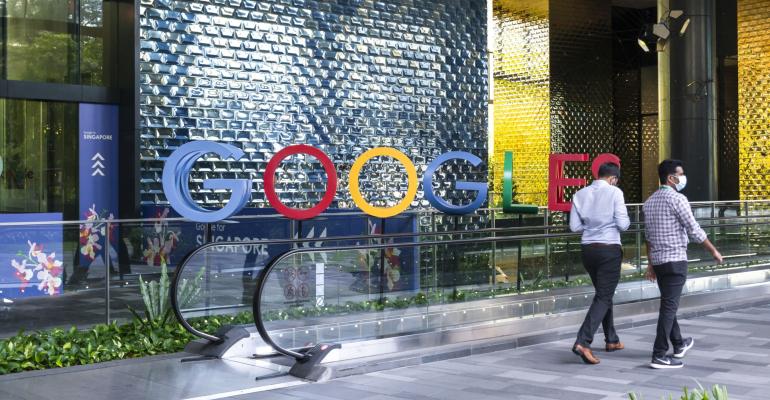 Image of people walking in front of an office with the word Google in front of it.