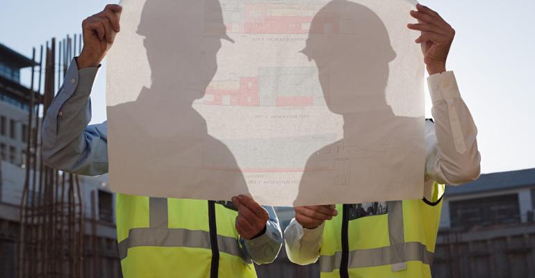 two men hold blueprints at data center construction site