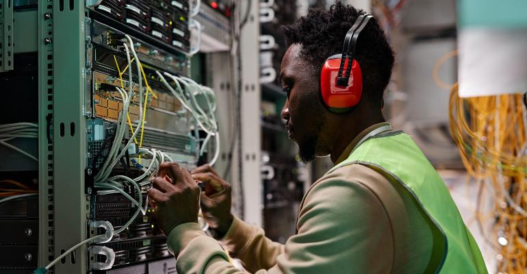 technician setting up a network in a server room wearing headphones