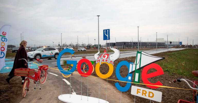 A woman passes by a Google themed barrier in front of a Google data center in Fredericia, Denmark (November 2020)
