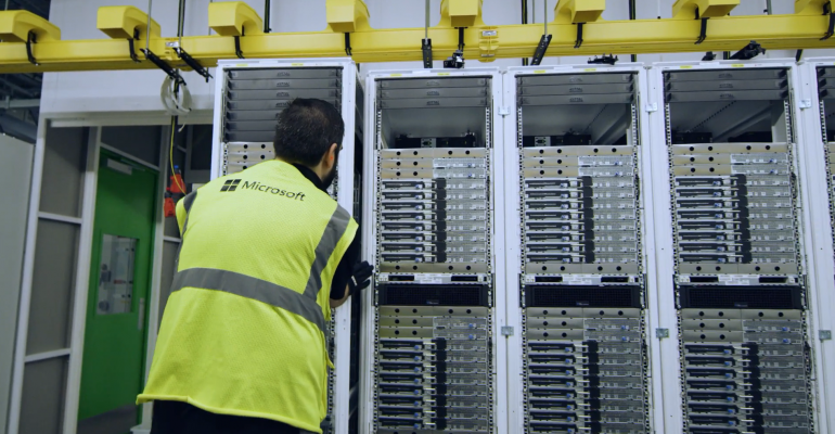 A Microsoft data center worker securing a rack of servers in place.