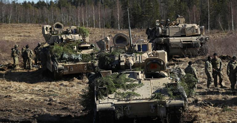 US soldiers stand near their M2A3 Bradley fighting vehicles and an M1 Abrams tank following a joint military combat exercise with Estonian soldiers on March 23, 2017 near Tapa, Estonia.