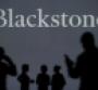 The Blackstone logo is seen on an LED screen in the background while a silhouetted person uses a smartphone in the foreground.