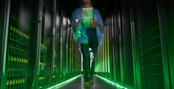 IT technician walking in dark, glowing server room