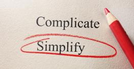 the words "complicate" and "simplify" on a paper with a red pencil