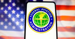 In this photo illustration, the United States Federal Aviation Administration (FAA) logo is displayed on a smartphone screen with a United States flag in the background.