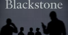 The Blackstone logo is seen on an LED screen in the background while a silhouetted person uses a smartphone in the foreground.