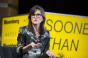 Image of investor Cathie Wood in front of yellow background. She is gesturing and speaking at an event.