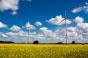 Two wind turbines with cloudy sky in the background and rapeseed field in the foreground