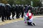 A woman kneels in front of law enforcement officers during a rally to protest against the presidential election results in Minsk on September 13, 2020. 