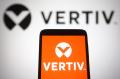 In this photo illustration, Vertiv Holdings Co logo is seen displayed on a smartphone and a pc screen.