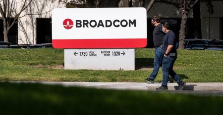 Two people walking in front of Broadcom headquarters in San Jose, California.
