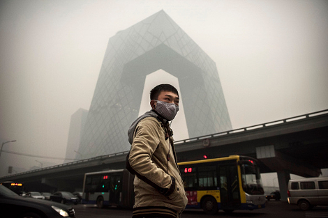 A Chinese man wears a mask as he waits to cross the road near the CCTV building during heavy smog on November 29, 2014 in Beijing. (Photo by Kevin Frayer/Getty Images)